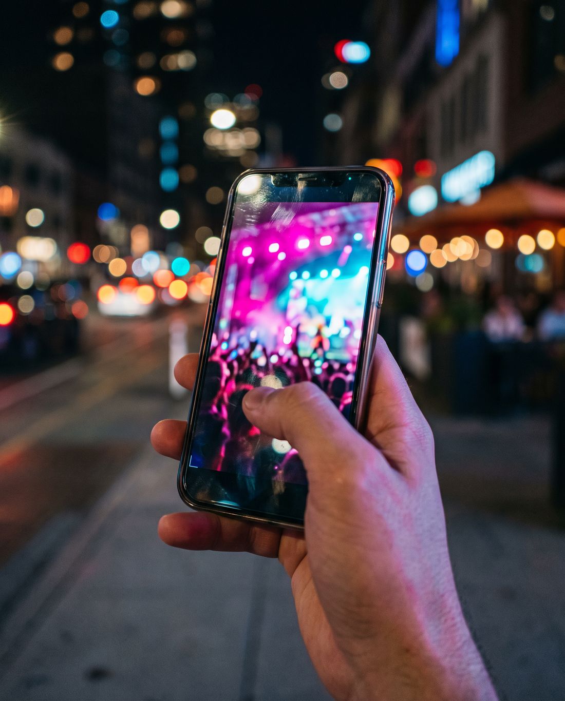 A hand scrolling a vertical video feed on a phone at night